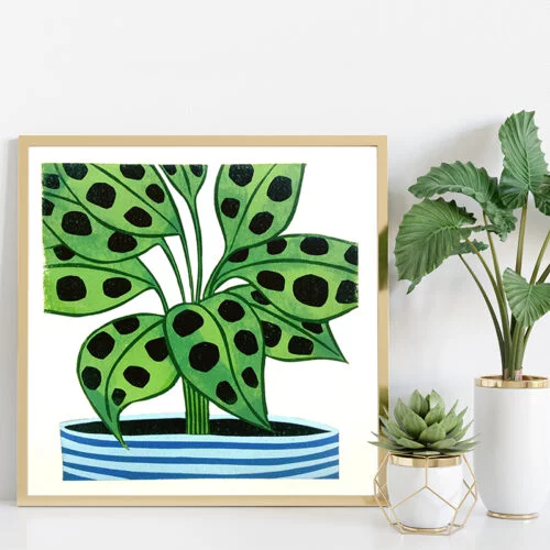 Maranta Plant Lino Print in a square light wooden frame on white shelf next to two plants
