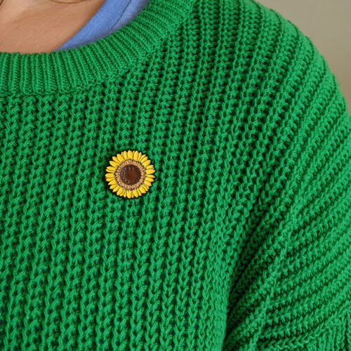 Yellow Sunflower Enamel Pin being worn on chunky green knit jumper