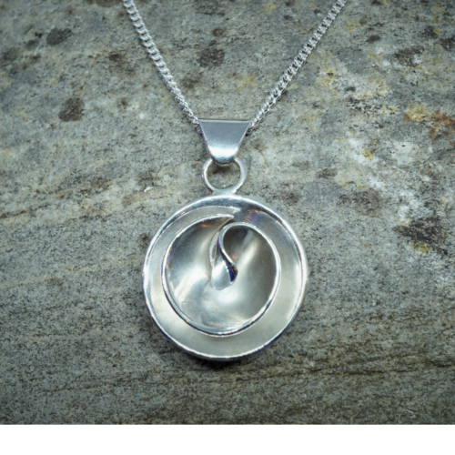 Contemporary circular sterling silver rose shaped pendant on chain with stone background.