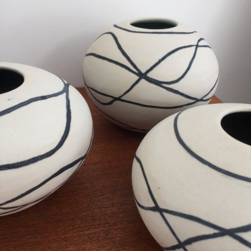 Wheelthrown vessels with a black inlaid wavy design.