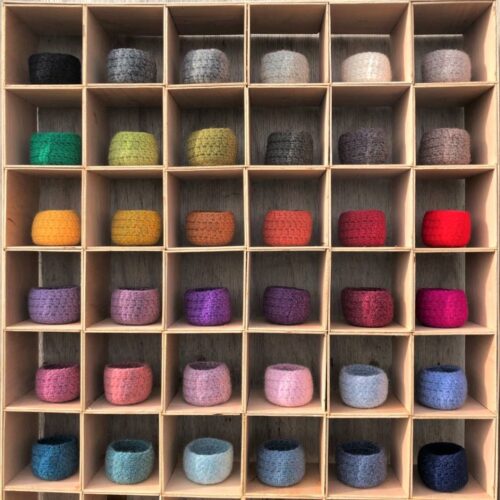 A display box filled with small felted bowls in 36 different colours