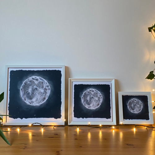 Three white Full Moon prints framed and in size order from large to small with a dark blue background