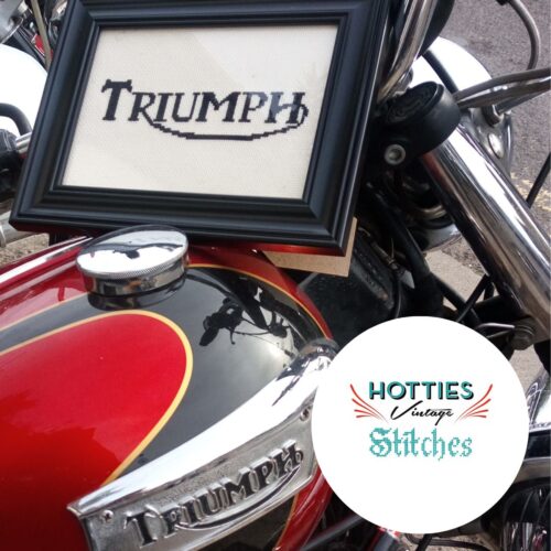 Triumph motorbike tank with a cross stitch version of the logo framaed on top