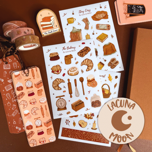 Flat lay of stationery products such as sticker sheets, washi tape, a journal, book marks and a journal clip. Colours are warm and cosy browns and oranges